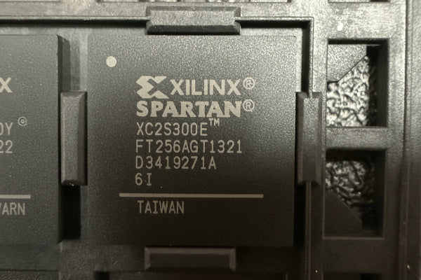 Xilinx Spartan FPGA chip with model number XC2S300E on a textured background